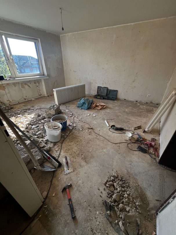 Unfertiger Raum mit Baustellenmaterialien und unebenen Bodenbelag.